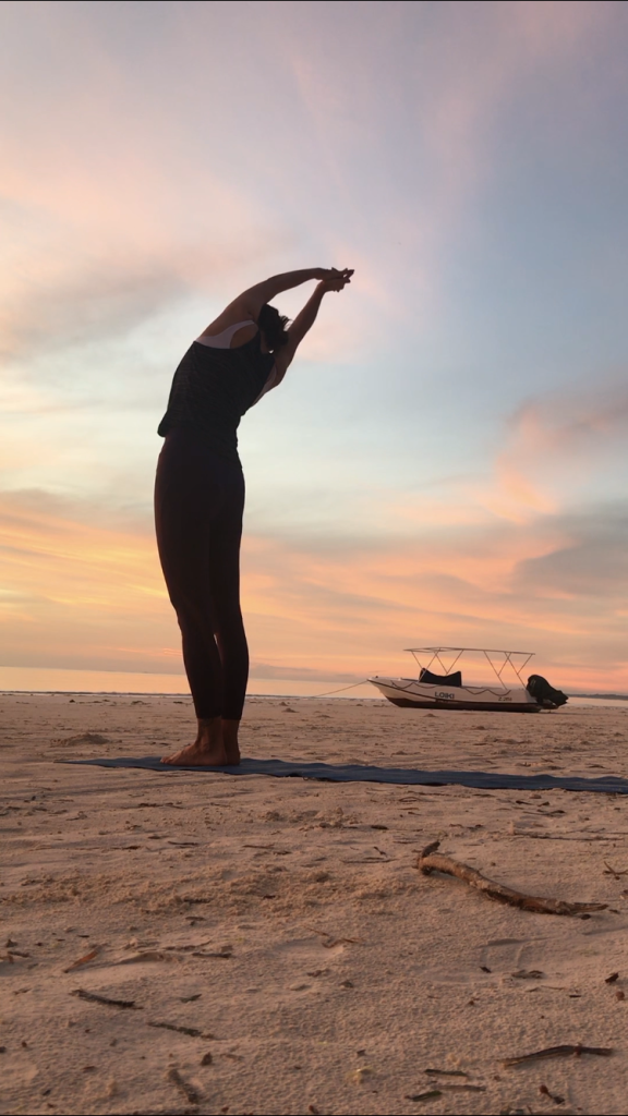 Jooga opettaja Rita Saari jooga asennossa hiekkarannalla Sansibarilla aamu auringossa